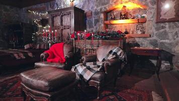 Empty comfortable living-room with Christmas decorations. Warm blankets on soft armchairs and candlesticks with red candles in the house. video