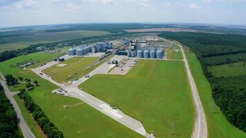 Panoramic view of a modern factory on green nature background. Grain elevators on field. Large agriculture complex among environment in summer. Aerial view. video