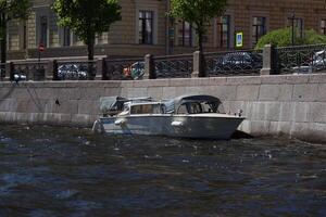 A Serene Boat Floating Gently by the Riverbank in an Urban Setting with Scenic Views photo