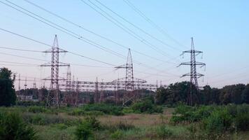 Lots of electricity towers on field. Large power station with many high-voltage electric lines with wires against the sky background. Transmission lines in green nature. video