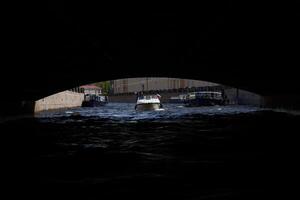 Boats gracefully glide through an archway as they navigate the calm, serene waters ahead photo