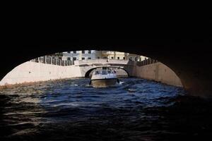 A beautifully scenic boat passage meanders gracefully beneath a historic and elegant archway photo