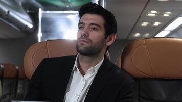 Business Travel, Businessman in a suit travels on airplane working on a tablet and speaking on the phone. Modern international business trip. Inflight digital tech connectivity. Global Business travel video