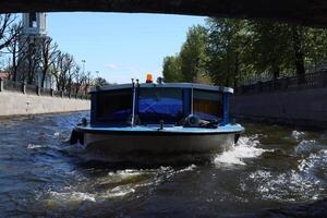 A boat skillfully navigating a vibrant waterway under a bridge in a lively urban setting photo