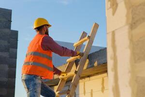 Construction worker inspecting building on ladder at sunset. photo