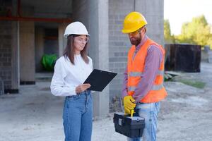 Construction worker and architect discussing blueprint at building site photo