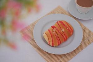 Delicious sweet bread with red icing on a plate with coffee photo
