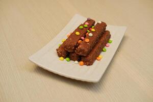 Chocolate Bars with Colorful Sprinkles on a White Plate photo