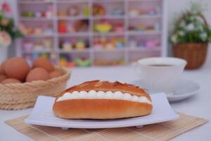 Delicious pastry with cream filling and almond flakes on a white plate. photo