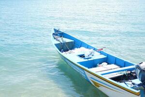 A blue fishing boat floating on the ocean under a bright sunny day photo