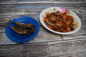 Freshly fried chili prawns and fish are placed on a plate, ready for a delicious seafood meal. photo