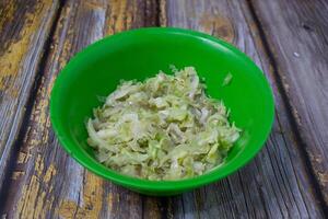 Warm shredded cabbage served in a bright green plastic bowl. photo
