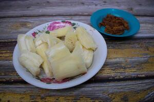 A simple, rustic meal of cassava and jaggery ready to enjoy on a vintage-style wooden table. photo