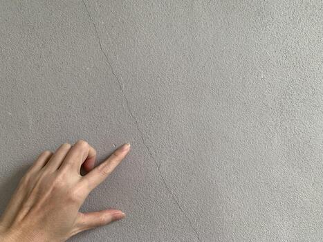 finger point gesturing with surface fracture on wall background photo