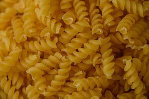 Macro view of dry fusilli pasta filling the frame. Spiral texture ideal for food design, packaging, or cooking visuals. photo