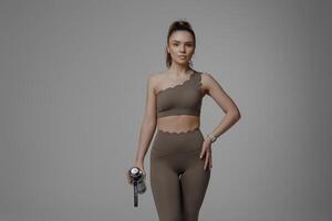 Fitness enthusiast in stylish activewear poses confidently with water bottle in a minimalistic studio setting during a workout session photo