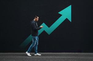 Man walking while using smartphone in front of rising arrow graphic, technology and growth concept, urban lifestyle, copy space on left photo