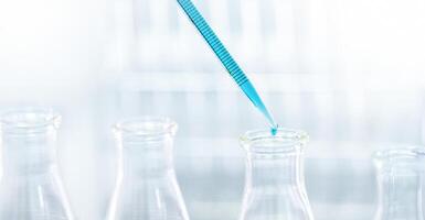 Doctor or scientist using pipette to drop a sample to test tube in medical research photo