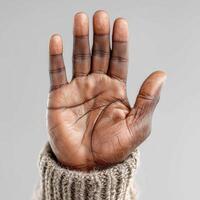 Close-up of an open hand of black man showcasing detailed skin texture and natural lines, with a cozy knitted sweater in the background, symbolizing warmth and connection photo