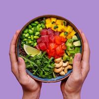 Poke bowl with salmon and tuna in hand on a purple background, photo