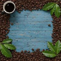 A cup of black coffee is placed within a frame formed by roasted coffee beans and green leaves on a textured blue wooden background photo