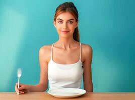 Woman sitting at a table with a fork and a plate of food photo