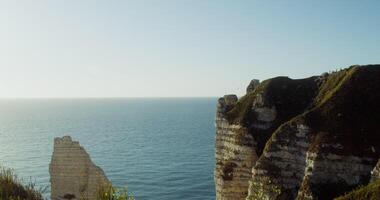 Picturesque view from top of the hill to the sea distance. Steep slopes of chalk cliffs with tops overgrown with dense green grass. Etretat, France. 4k , red komodo photo