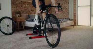 A young man of European appearance exercising on an exercise bike in a modern home interior. Indoor cardio. Cycling at home using a bike station photo