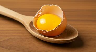 An egg is broken in half on a wooden spoon photo