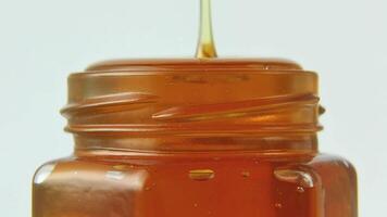 Golden honey dripping steadily from glass jar creating amber streams video