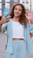 Preteen girl blogger taking selfie on smartphone call online with subscribers in city street video