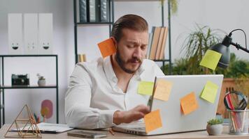 Tired sad exhausted businessman working on laptop at office with many sticker tasks, panic attack video