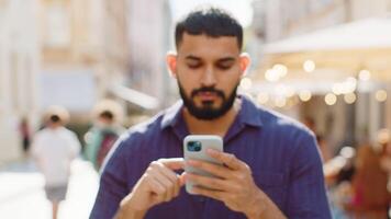 Young man use smartphone typing text messages browsing internet finishing work looking at camera video