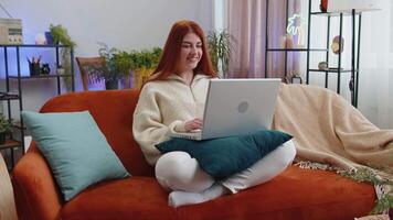 Woman sitting on home couch, looking at camera, making conference call with friends or family video