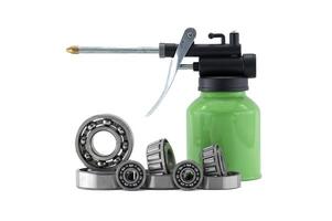 An oil can with grease and ball bearings are displayed on a clean white background. photo