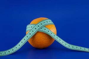 Orange wrapped with a measuring tape, representing diet and weight loss. photo