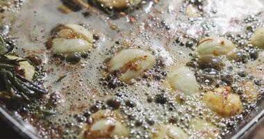 barbecue party, garlic and thyme languish in butter in a frying pan for meat steaks, oil bubbles are illuminated by firelight, close-up footage of grilling steaks video