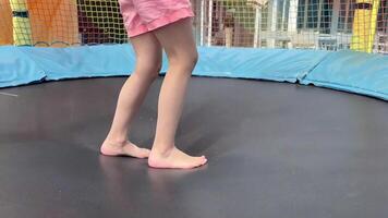 A child happily jumps barefoot on a trampoline at a playground on the beach in summer. video