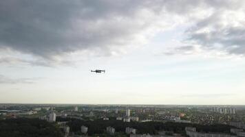 A hovering drone takes off against a cloudy sky and forest background.The quadcopter is flying towards the forest and residential area of the city. video