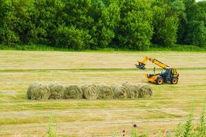 a tractor is working on a field with hay bales photo