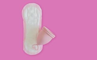 A silicone menstrual cup on the sanitary pad isolate on pink background with copy space. photo