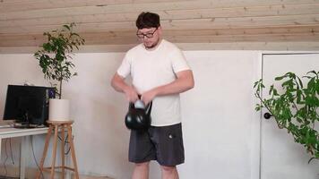 man training with kettlebell at home while working from the computer from home, performing workout between working sessions video