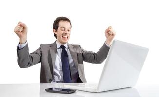 Happy executive man looking a laptop computer with arms raised in success photo