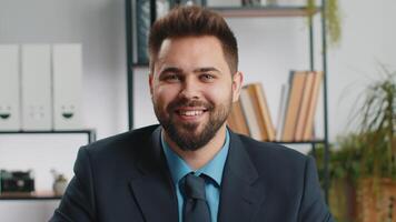 Portrait of happy smiling bearded Caucasian business man at office look away turn head at camera video