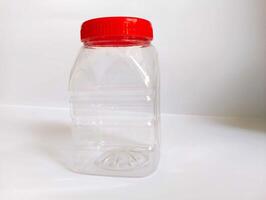 A empty transparint bttle with rad cap on a white background. photo