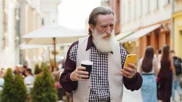 Elderly old man use smartphone typing text messages browsing internet finishing work chatting online video