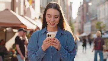 Young woman use smartphone typing text messages browsing internet finishing work looking at camera video