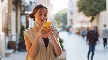 Young woman use smartphone typing text messages browsing internet finishing work looking at camera video