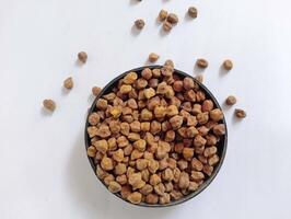 Raw black chickpeas in round bowl on white background. photo