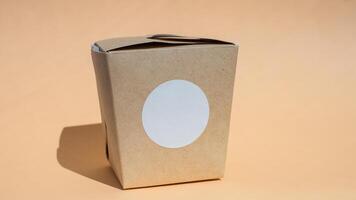 Brown kraft paper takeout box with blank label on neutral background photo